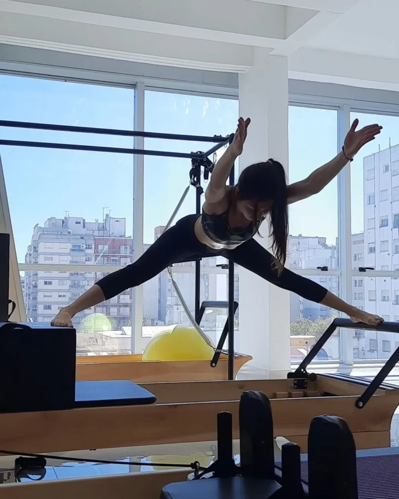 Alumna haciendo una apertura de piernas sobre el Reformer en una clase semipersonalizada