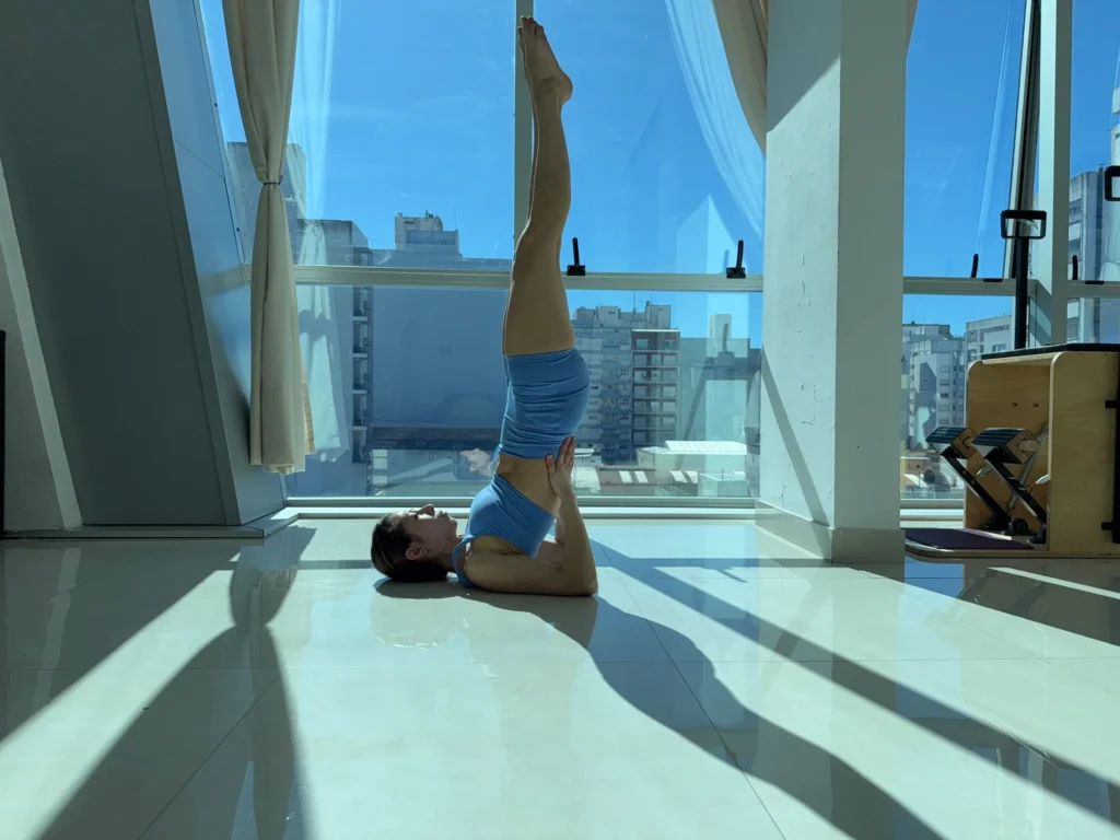 Alumna en posición invertida con las piernas elevadas en vertical, ejercicio del repertorio de Pilates Mat